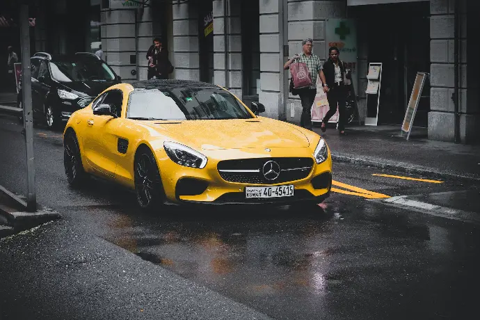 yellow Mercedes-Benz coupe on asphalt road near concrete building